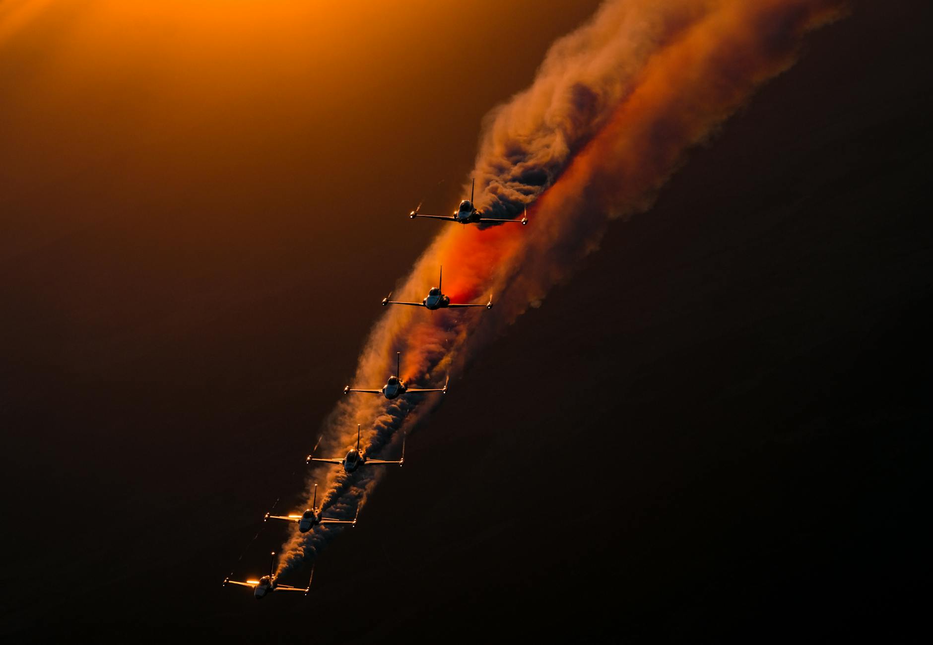 Stunning jet formation with smoke trails at sunset, showcasing aerial precision.