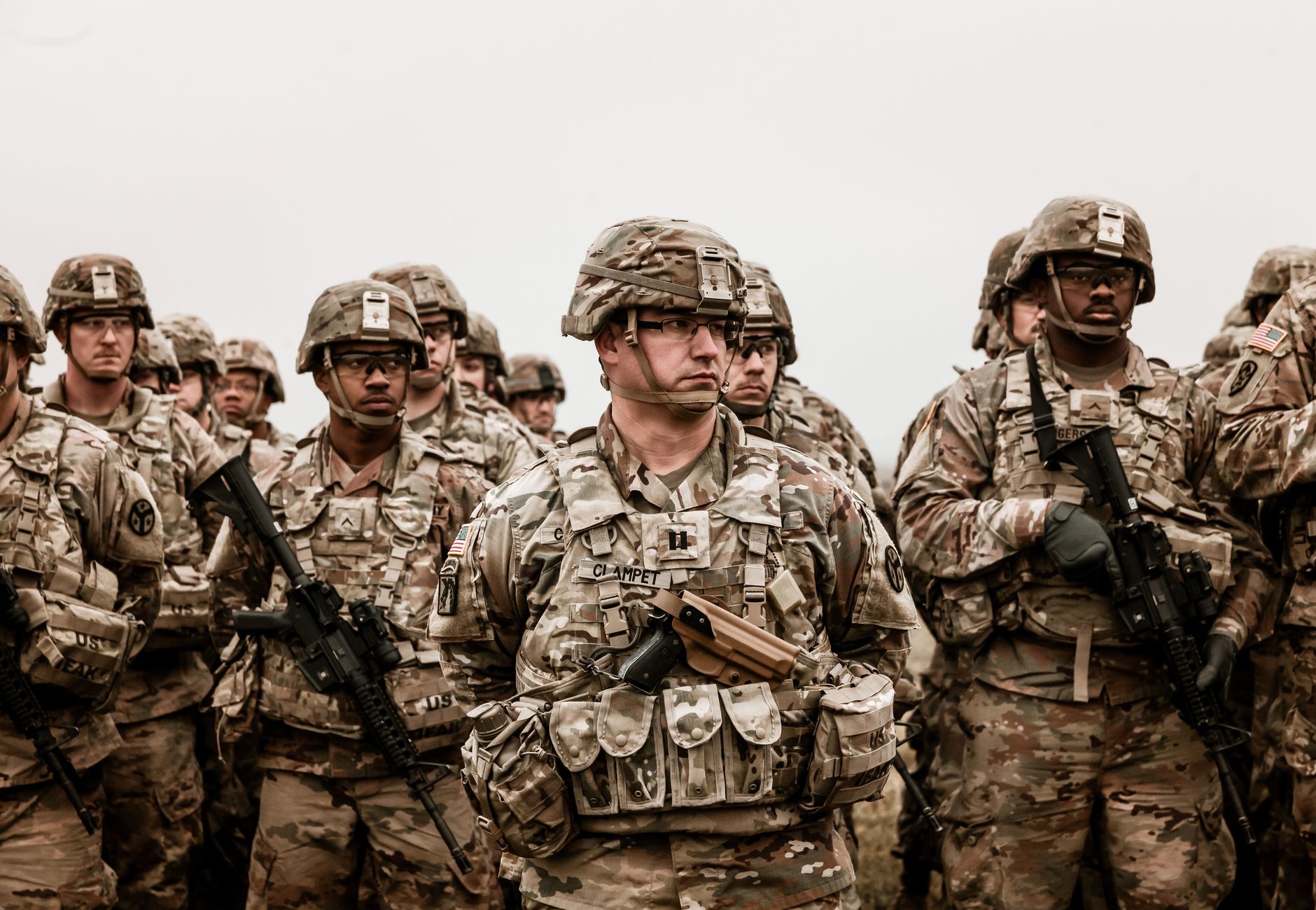 A diverse group of soldiers in camouflage uniforms standing with rifles.