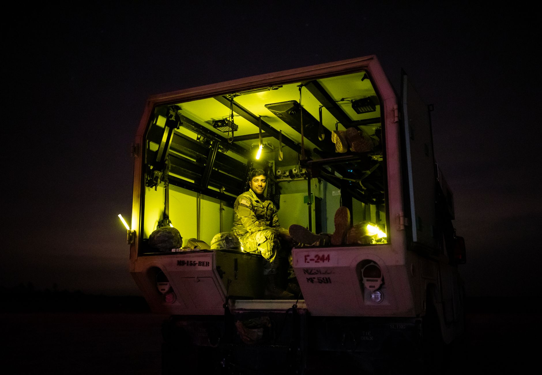 Soldier inside a dimly lit military vehicle at night, creating a dramatic scene.